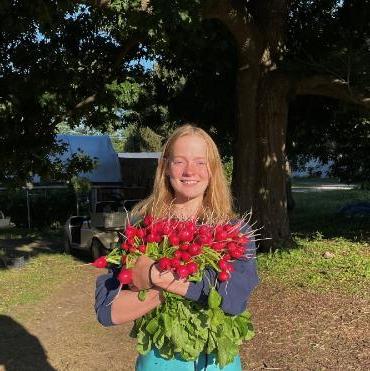 A headshot of Nikki outside while holding a large bouquet of flowers